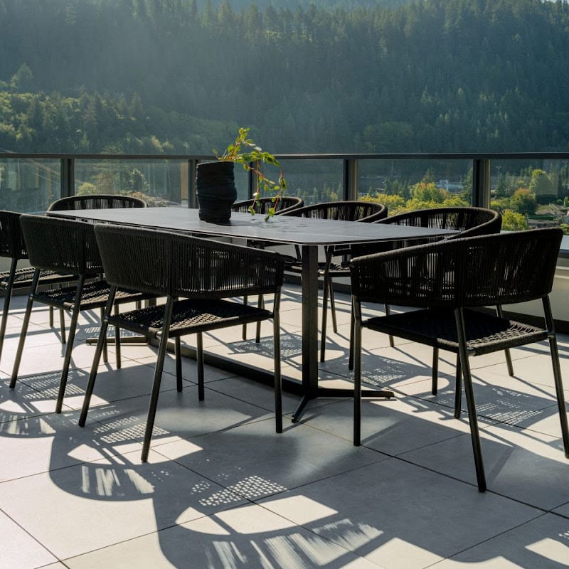 Wide Angle View Of The Afton Outdoor Dining Chair With Black Cord And Black Frame On A Patio Next to a Black Table