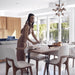 Woman Setting Table With Several Aubrey Side Chairs in Alesund Fabric and Walnut Wood Finish Surrounding