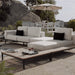 A Francis Outdoor End Table Next to a Francis Chaise in a Backyard at an Angled View