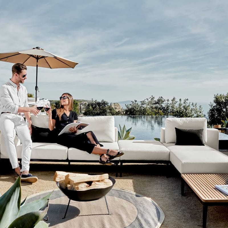 Couple Enjoying Wine With Pool In The Background While Sitting On The Francis Outdoor Modular Sectional Sofa In Palisades Color With Black Base