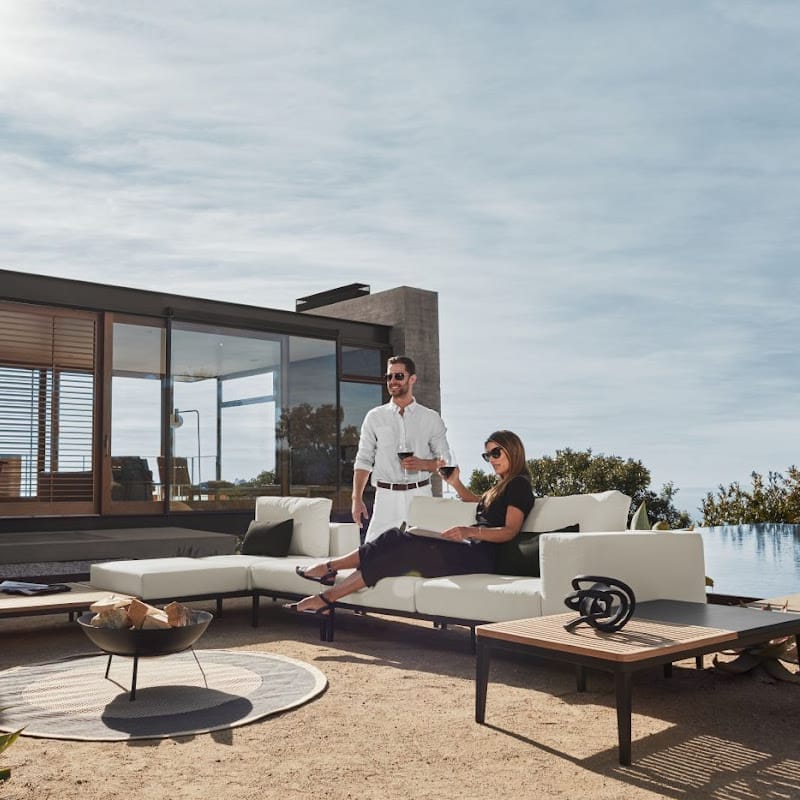 Angled View of a Couple Using The Francis Outdoor Modular Left Chaise And Sofa In Palisades Color Shot In Backyard