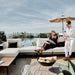 Front Facing View of a Couple Using The Francis Outdoor Modular Left Chaise And Sofa In Palisades Color Shot In Backyard