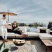 Front Facing View of a Couple Using The Francis Outdoor Modular Right Chaise And Sofa In Palisades Color Shot In Backyard