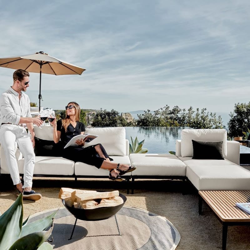 Front Facing View of a Couple Using The Francis Outdoor Modular Right Chaise And Sofa In Palisades Color Shot In Backyard