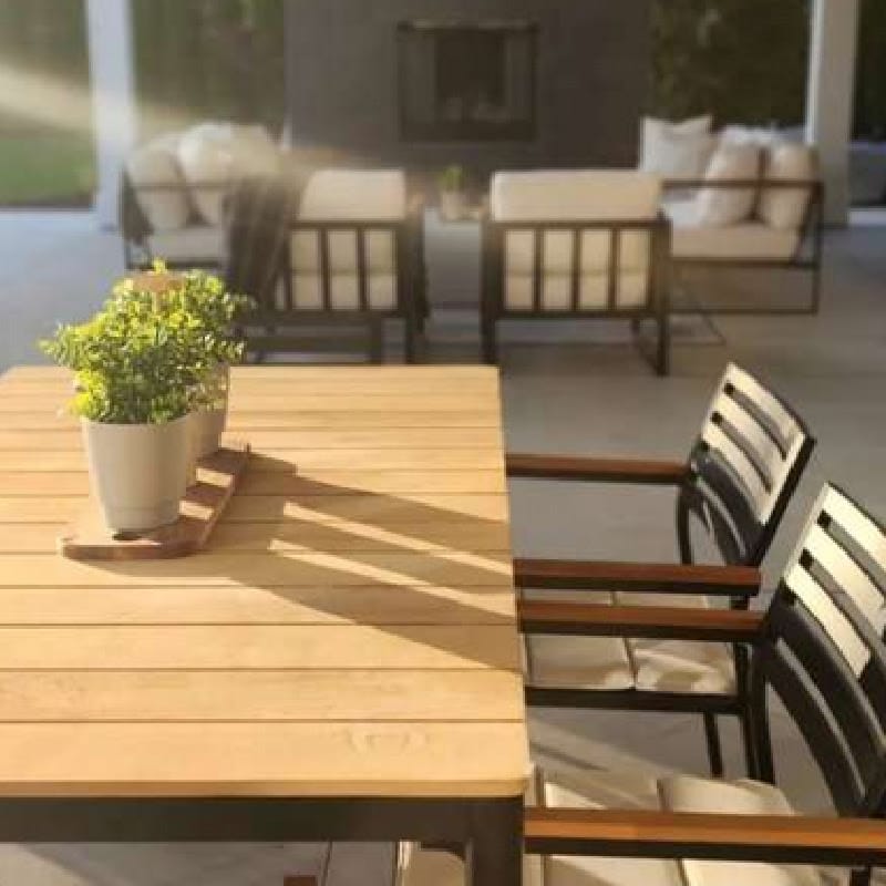 Close Up View Of Two Linnea Outdoor Dining Chairs In Palisades Fabric With Black Frame Next To a Spencer Outdoor Dining Table