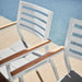 Two Linnea Outdoor Dining Chairs In Encino Fabric With White Frame Next To a Pool