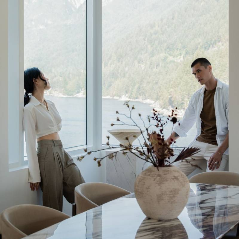 Close Up View of Couple Next to Several Solana Dining Chairs in Trento Taupe Fabric and Black Base