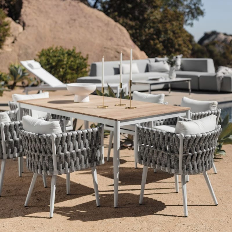 White Spencer Outdoor Dining Table With Pierre Outdoor Chairs On a Patio With Couch In The Background