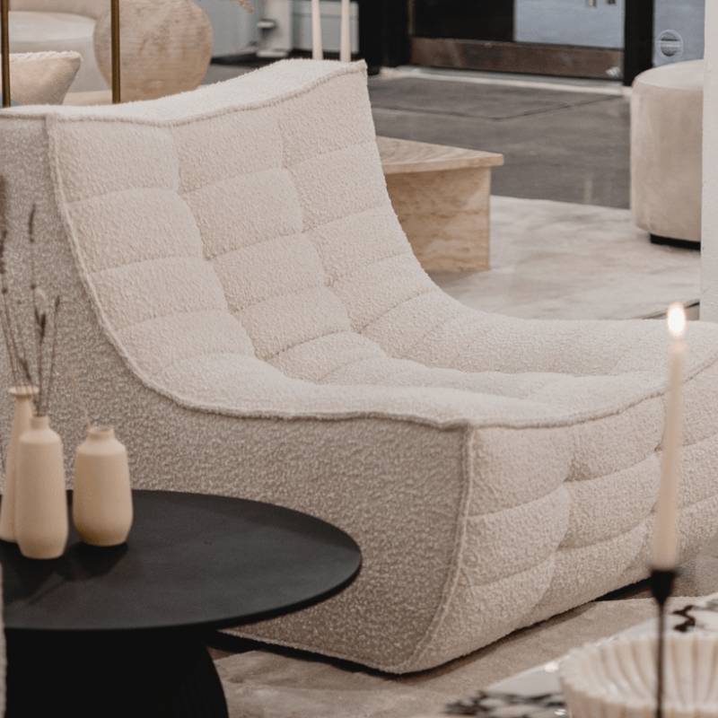 Close Up Side View of The Tanner Armless Modular Sectional Piece With Pearl Fabric Next to a Black Side Table