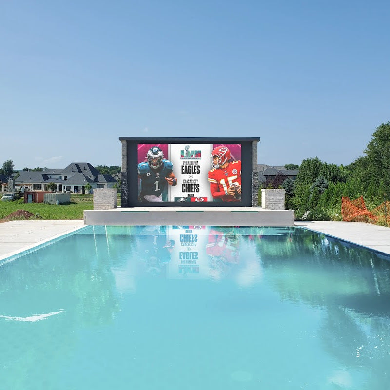 Yolo Outdoor TV Wall Mounted at The Edge of a Pool With House in The Background