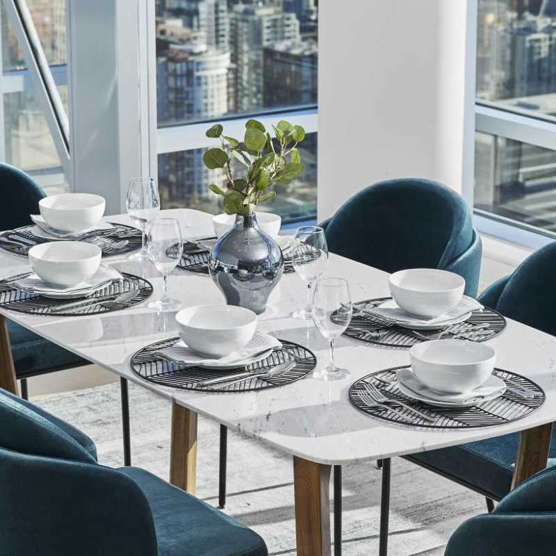 Angled Close Up View of The Evelyn Dining Table in White Carrara Marble in The Corner of a Dining Area Overlooking a City View