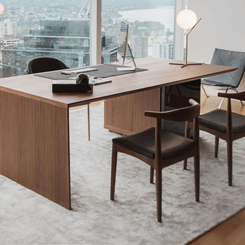 Angled View of The Gia Desk With Walnut Veneer Finish and Black Pietra Ceramic Base in an Office Overlooking The City