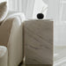 Close Up View of The Liza Side Table in White Carrara Marble in a Living Room on The Right Side of a Sofa