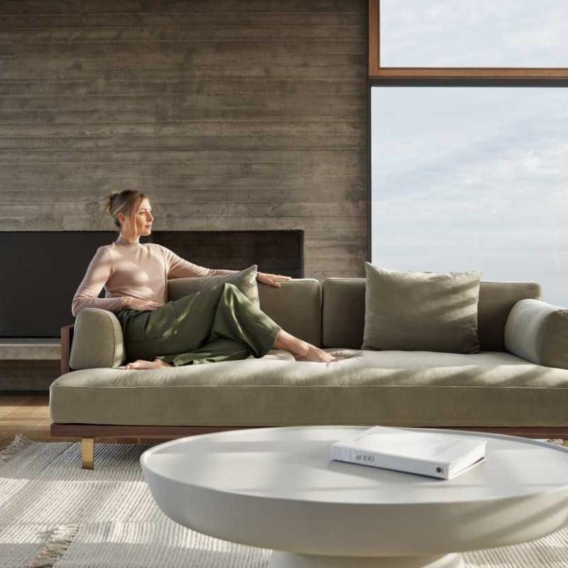 Close Up of Woman Sitting of The Maria Sofa in Olive Green Fabric and Color in a Living Room