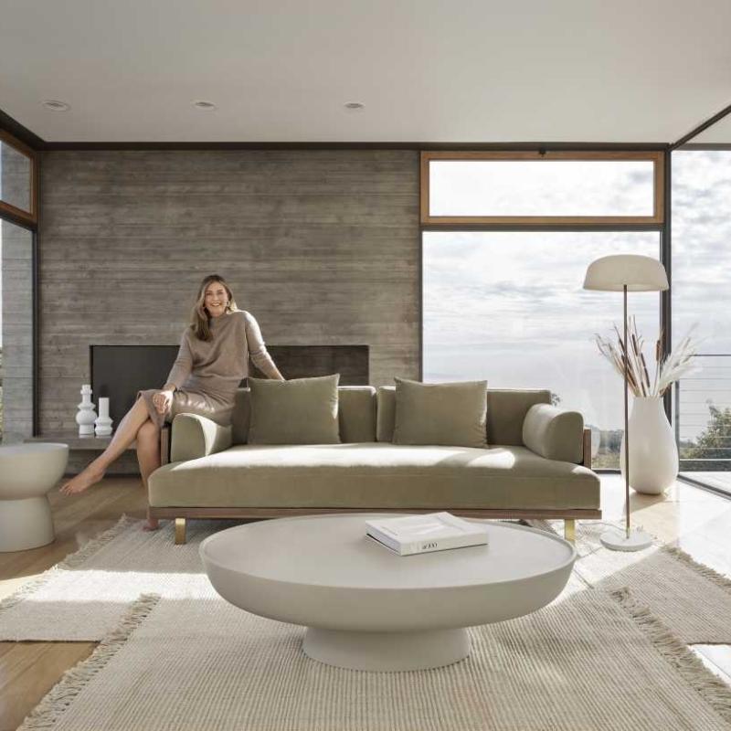 Woman Sitting on The Maria Sofa in Warm Taupe Fabric and Color in a Living Room