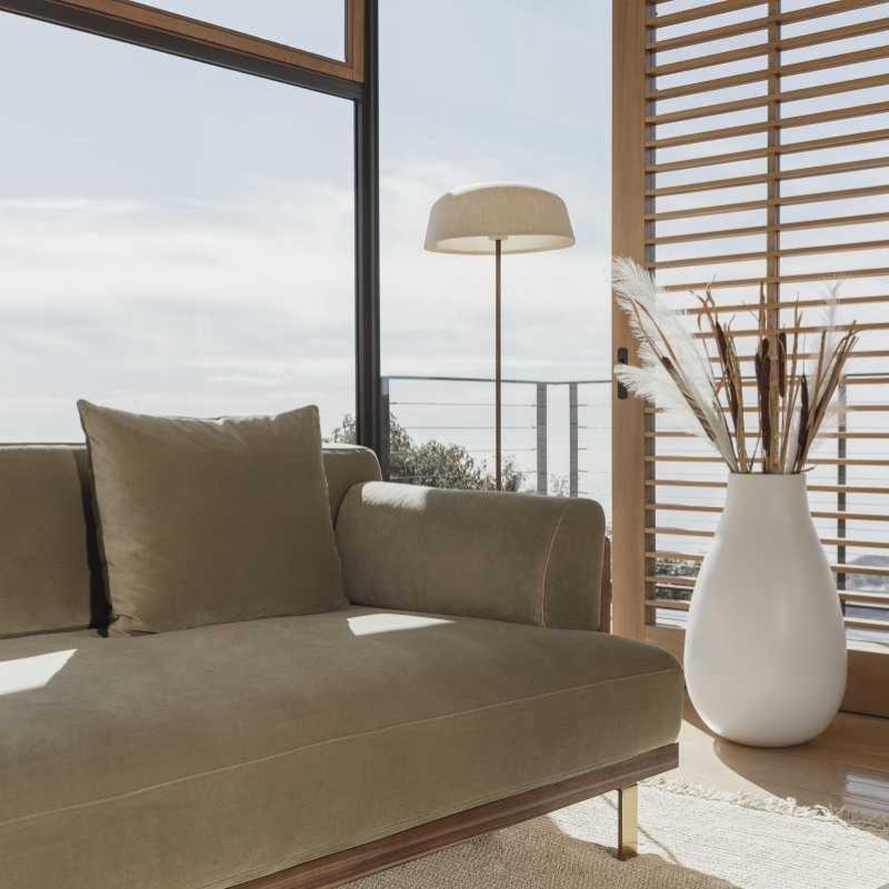 Close Up View of The Maria Sofa in Warm Taupe Fabric and Color Next to a Window in a Living Room