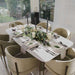 Angled Top View of The Solana Dining Table With a White Carrara Marble Surface and Antique Brushed Brass Base in a Dining Area With Six Place Settings