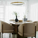 Angled Side View of The Solana Dining Table With a White Carrara Marble Surface and Antique Brushed Brass Base in a Dining Area Next to a Window