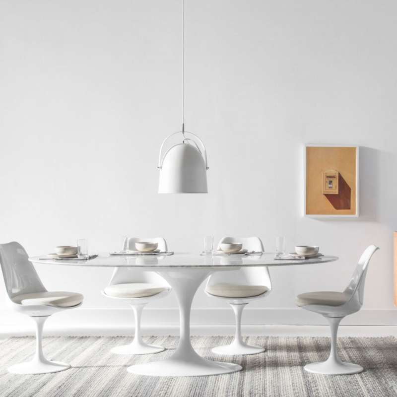 The Tulip Table Oval in White Carrara Marble in a Dining Area With Four Chairs