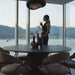 Woman Drinking Next to Uma Dining Chairs in Latte Fabric and Color at a Dining Table Next to Window 